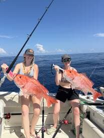 Two anglers proudly displaying their large Red Snapper while fishing offshore, showcasing a successful day on the water.