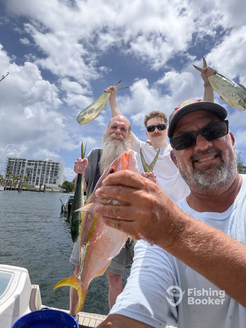 A group of anglers proudly displaying their catch, including a colorful Yellowtail Snapper and Mahi Mahi, while enjoying a sunny day on the water.