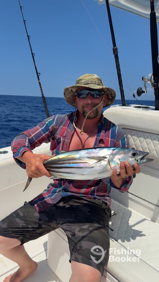 Angler proudly displaying a vibrant fish on a fishing boat, showcasing a successful day on the water.