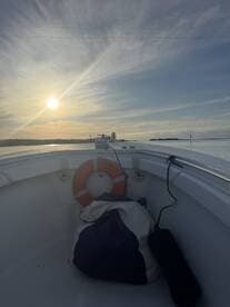 A serene view from the interior of a boat, showcasing a life ring and a bag, with a beautiful sunset over the water.