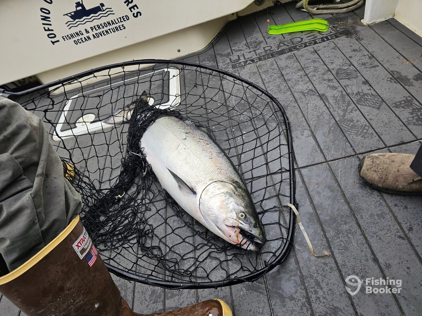 A large salmon is caught and resting in a net on the deck of a fishing boat, showcasing the fishing experience.