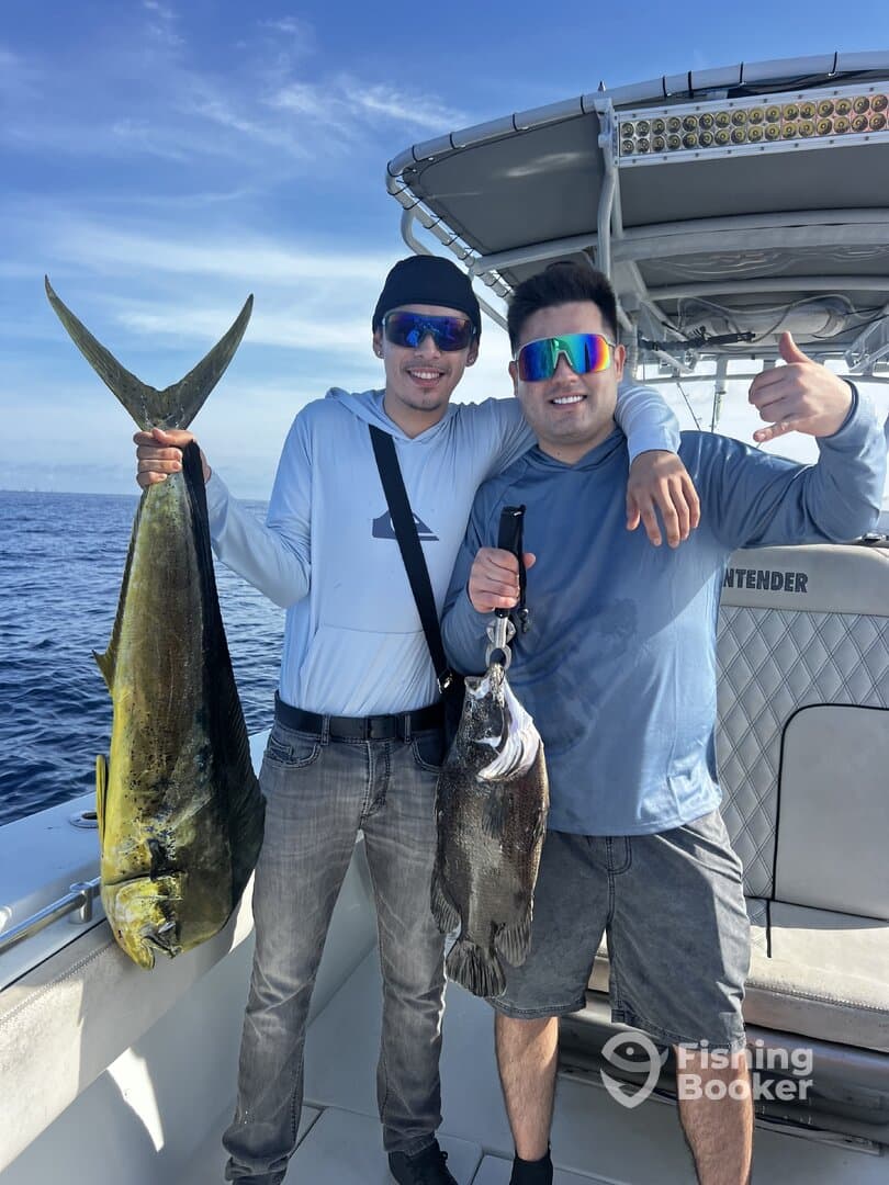 Two anglers proudly displaying their catch, a Mahi Mahi and a Grouper, while enjoying a day on the water.