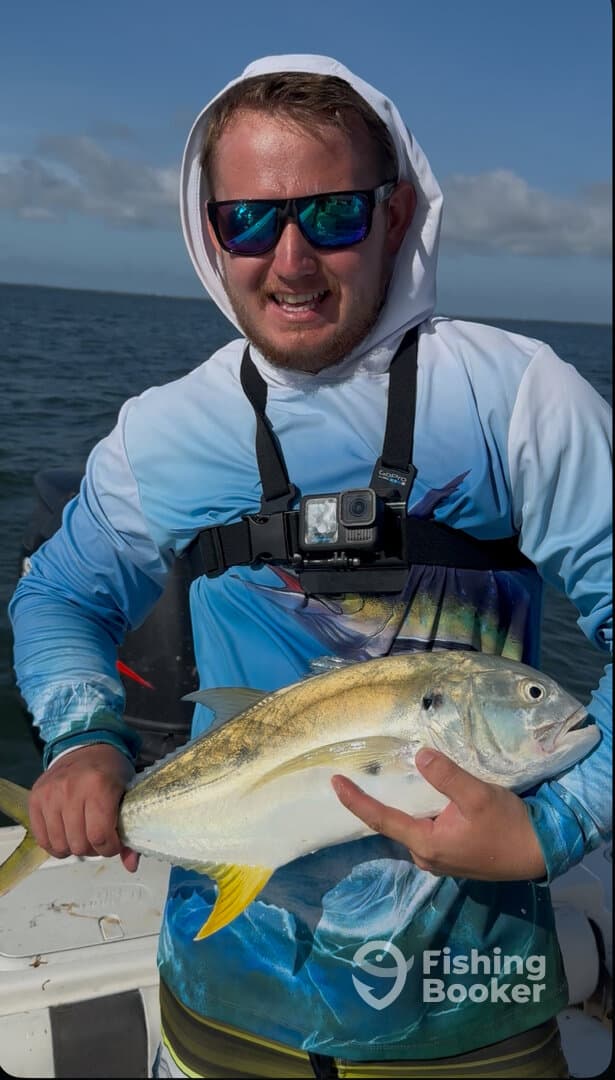 Angler proudly displaying a large Yellowtail at sea, showcasing a successful fishing trip.