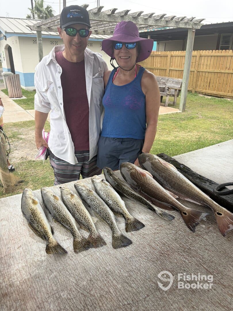 A couple proudly displaying their catch of Speckled Trout after a successful fishing trip at the dock.