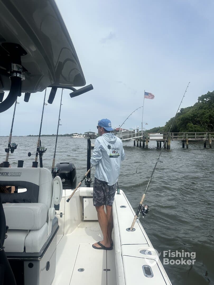 A fisherman casting from a center console boat in a scenic waterway, showcasing a relaxed fishing environment.