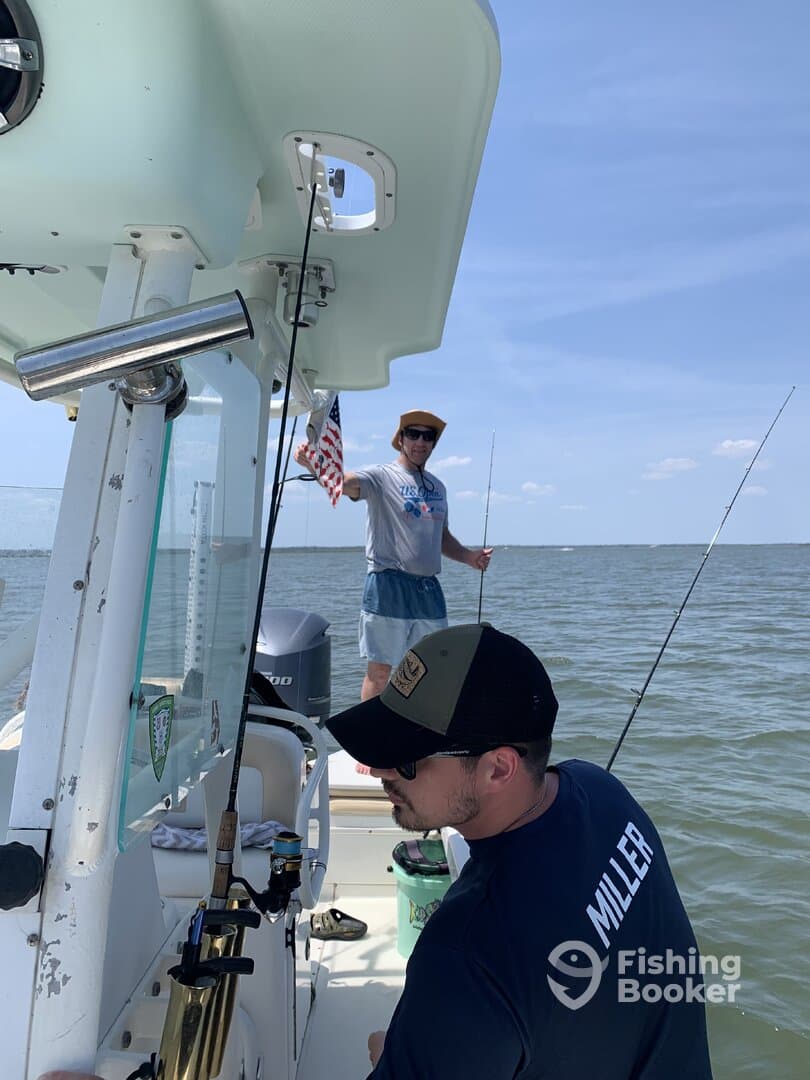 Two anglers enjoying a fishing trip on a boat, with one holding an American flag and the other focused on their fishing gear.