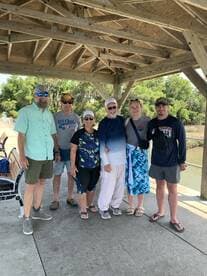 A group of six individuals gathered under a pavilion, likely after a fishing trip, showcasing a friendly atmosphere.
