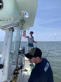 Two anglers enjoying a fishing trip on a boat, with one holding an American flag and the other focused on their fishing gear.