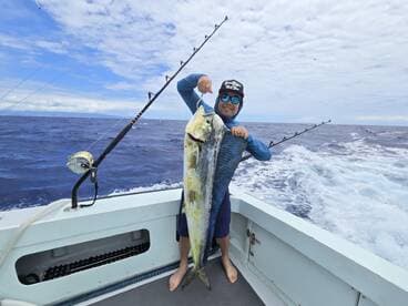 Angler proudly displaying a large Mahi Mahi while fishing offshore, showcasing a vibrant blue ocean backdrop.