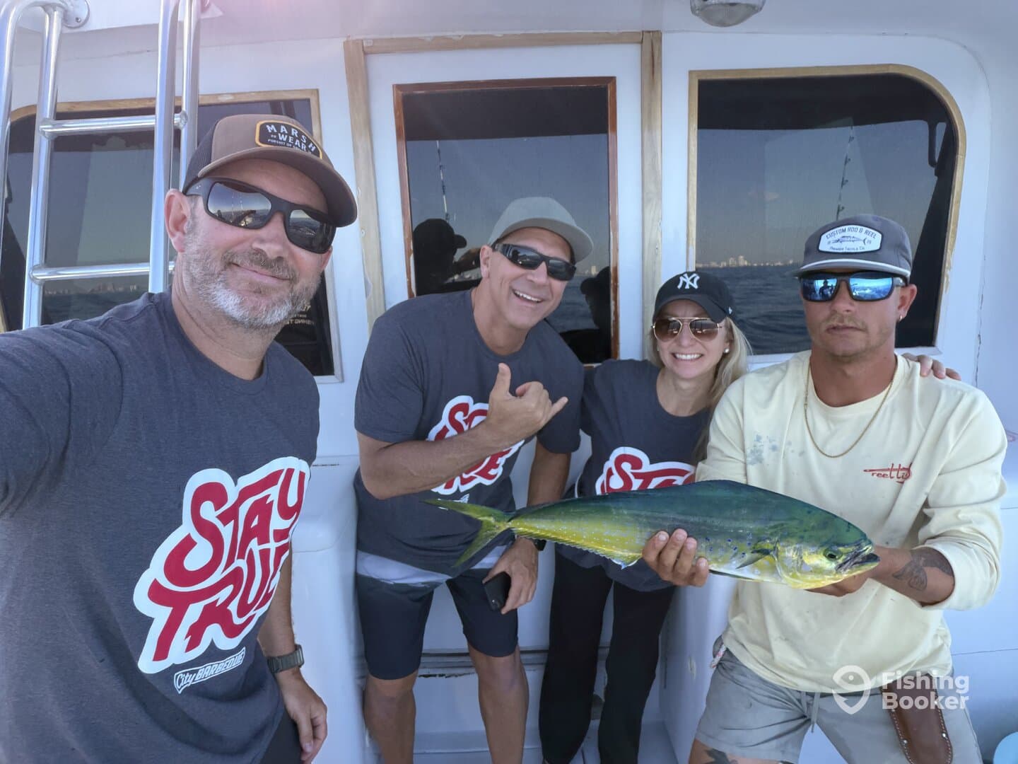 Group of anglers proudly displaying a vibrant Mahi Mahi aboard a fishing charter, showcasing a successful day on the water.