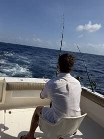 A solo angler casting lines from a boat in open waters, enjoying a day of deep-sea fishing.