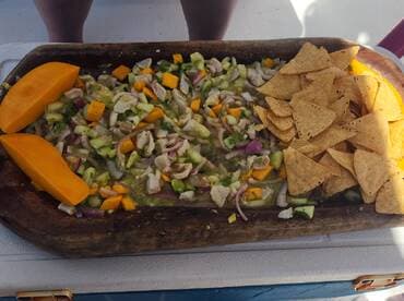 A vibrant platter of ceviche with fresh ingredients and tortilla chips, likely enjoyed on a fishing trip.