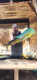 Angler proudly displaying a large Mahi Mahi at a tropical fishing lodge, showcasing a successful day on the water.