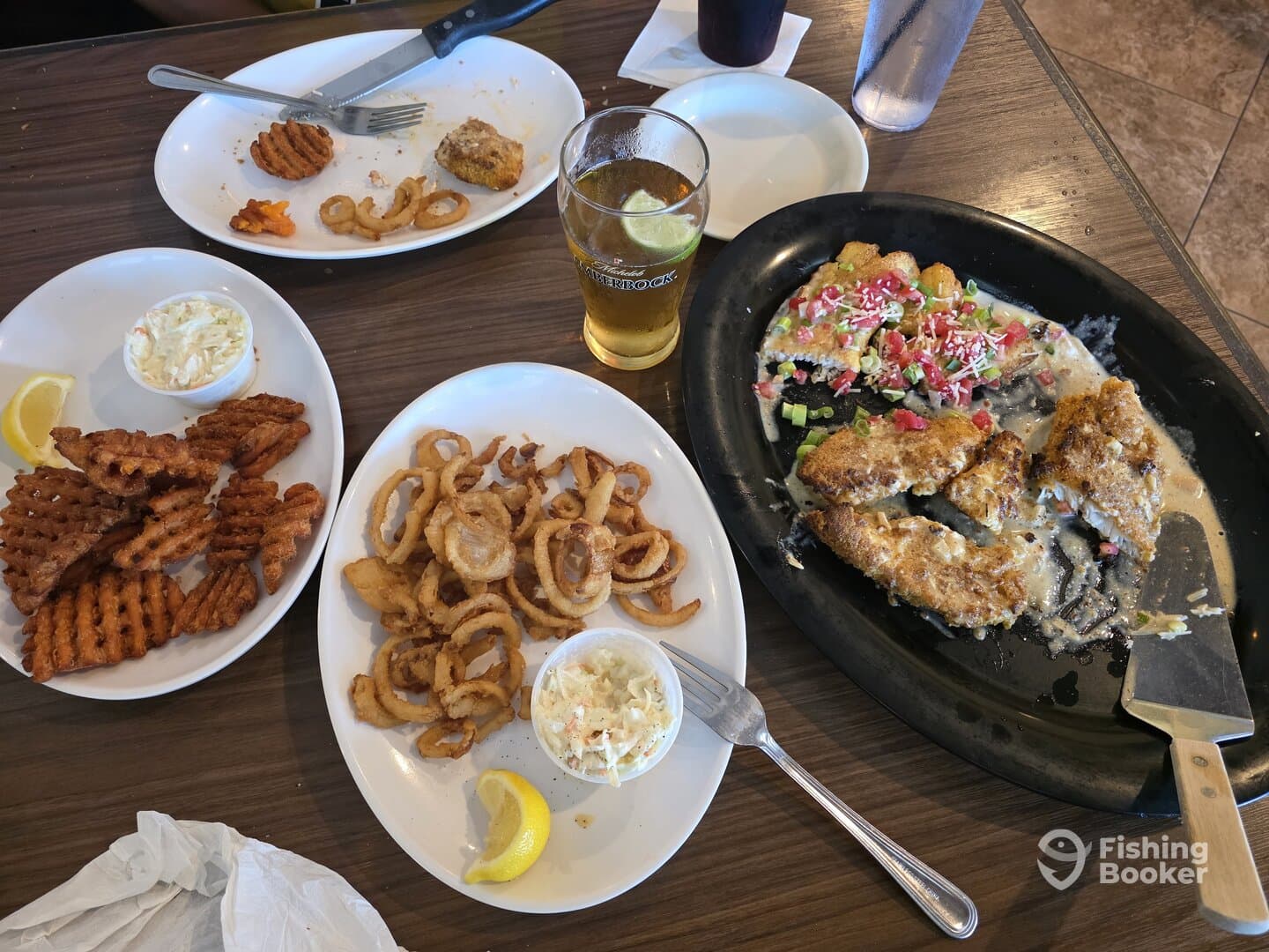 A table spread featuring various fried foods and a drink, likely enjoyed after a fishing trip.