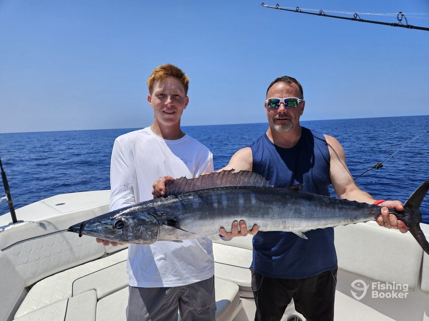 A young angler and an adult proudly display a large Wahoo caught during a deep-sea fishing trip.