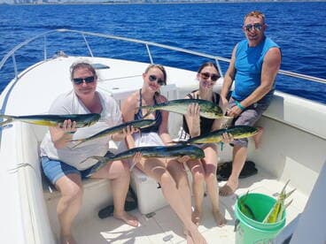 A family proudly displaying their catch of Mahi Mahi while enjoying a sunny day on the water.