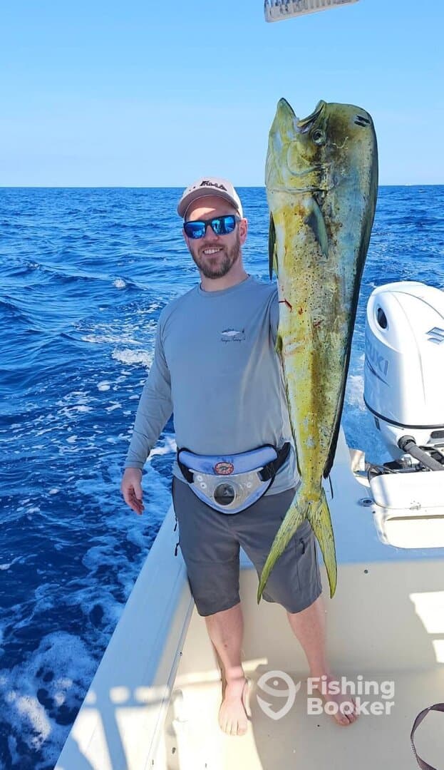 Angler proudly displaying a vibrant Mahi Mahi while fishing offshore, showcasing a successful day on the water.