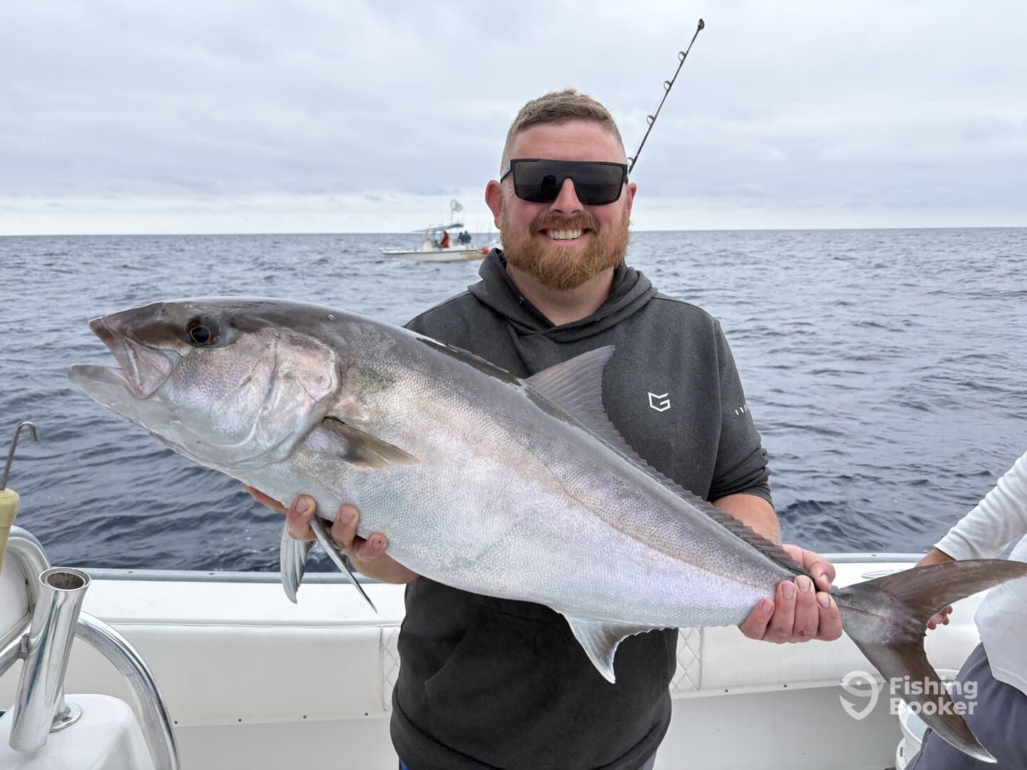 Angler proudly displaying a large Halibut while fishing offshore, showcasing a successful day on the water.