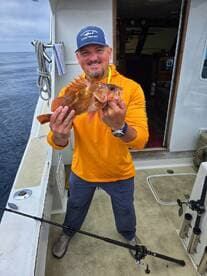 Angler proudly displaying a vibrant Rockfish caught during a deep-sea fishing trip.