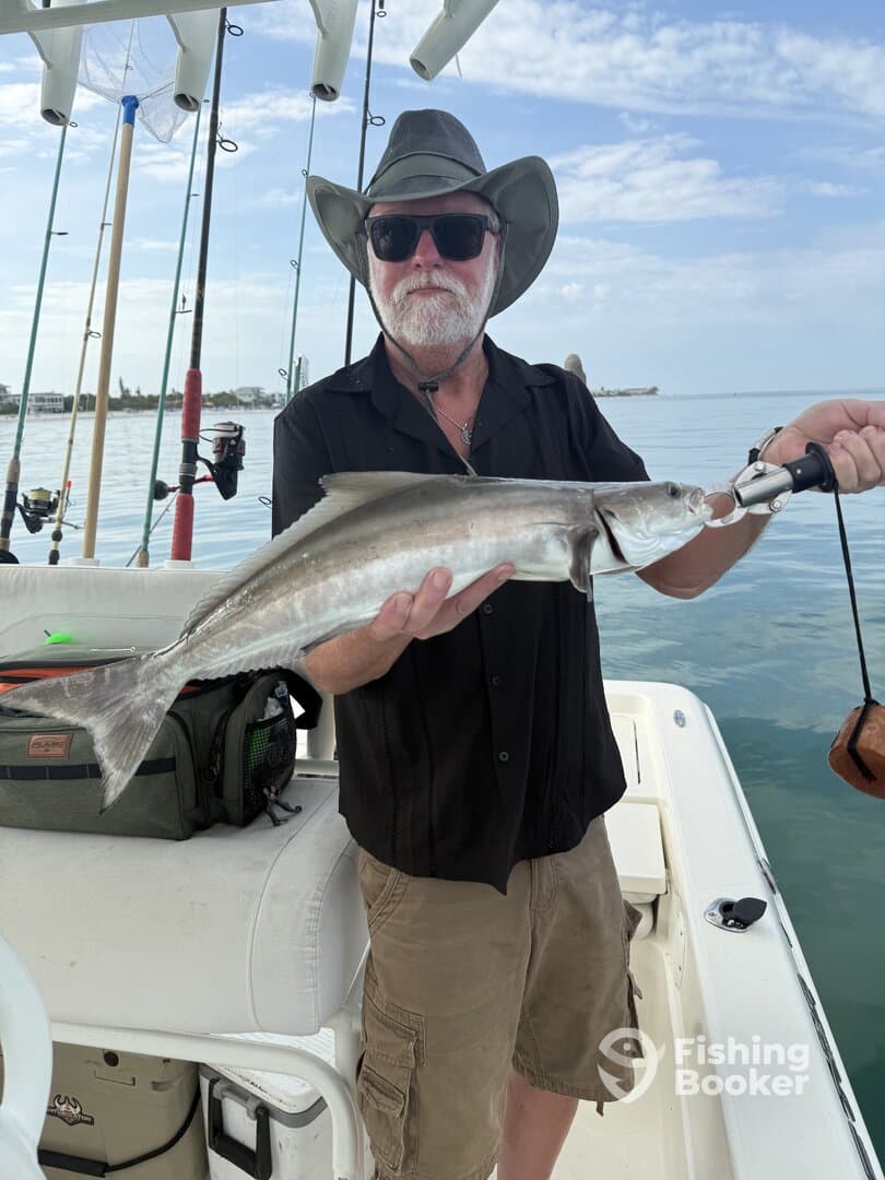 An angler proudly displaying a freshly caught fish aboard a fishing boat, showcasing a successful day on the water.