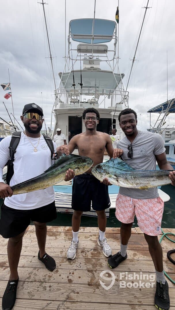 Three anglers proudly displaying their catch of Mahi Mahi at the dock after a successful fishing trip.