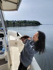 A young angler joyfully holding a freshly caught rockfish on a calm day aboard a fishing boat.