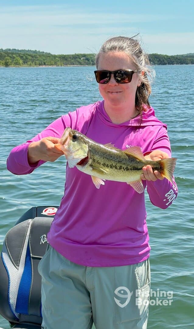 Angler proudly displaying a large Largemouth Bass while fishing on a sunny day.