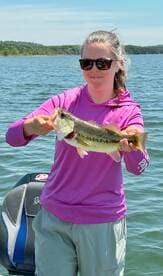 Angler proudly displaying a large Largemouth Bass while fishing on a sunny day.
