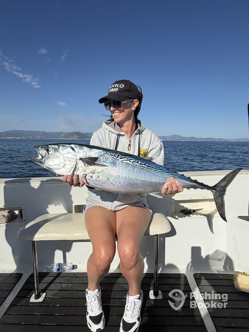 A smiling angler proudly displays a large fish while enjoying a sunny day on the water.