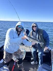 Two anglers proudly displaying a Walleye while fishing on a sunny day, showcasing a fun group outing on the water.