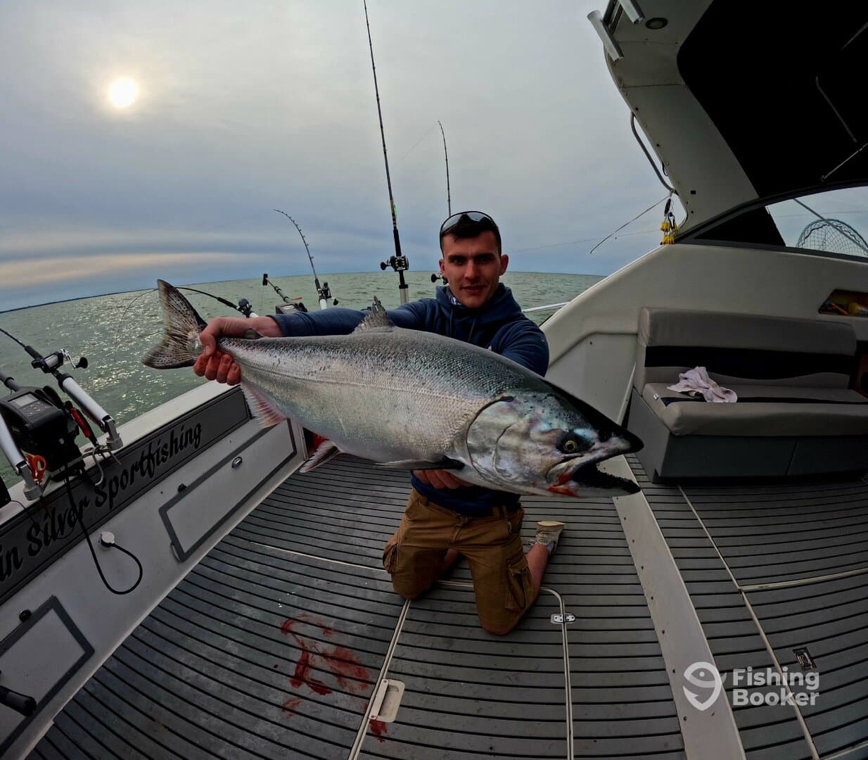 Angler proudly displaying a large Salmon on a fishing charter in open waters, showcasing the thrill of sport fishing.