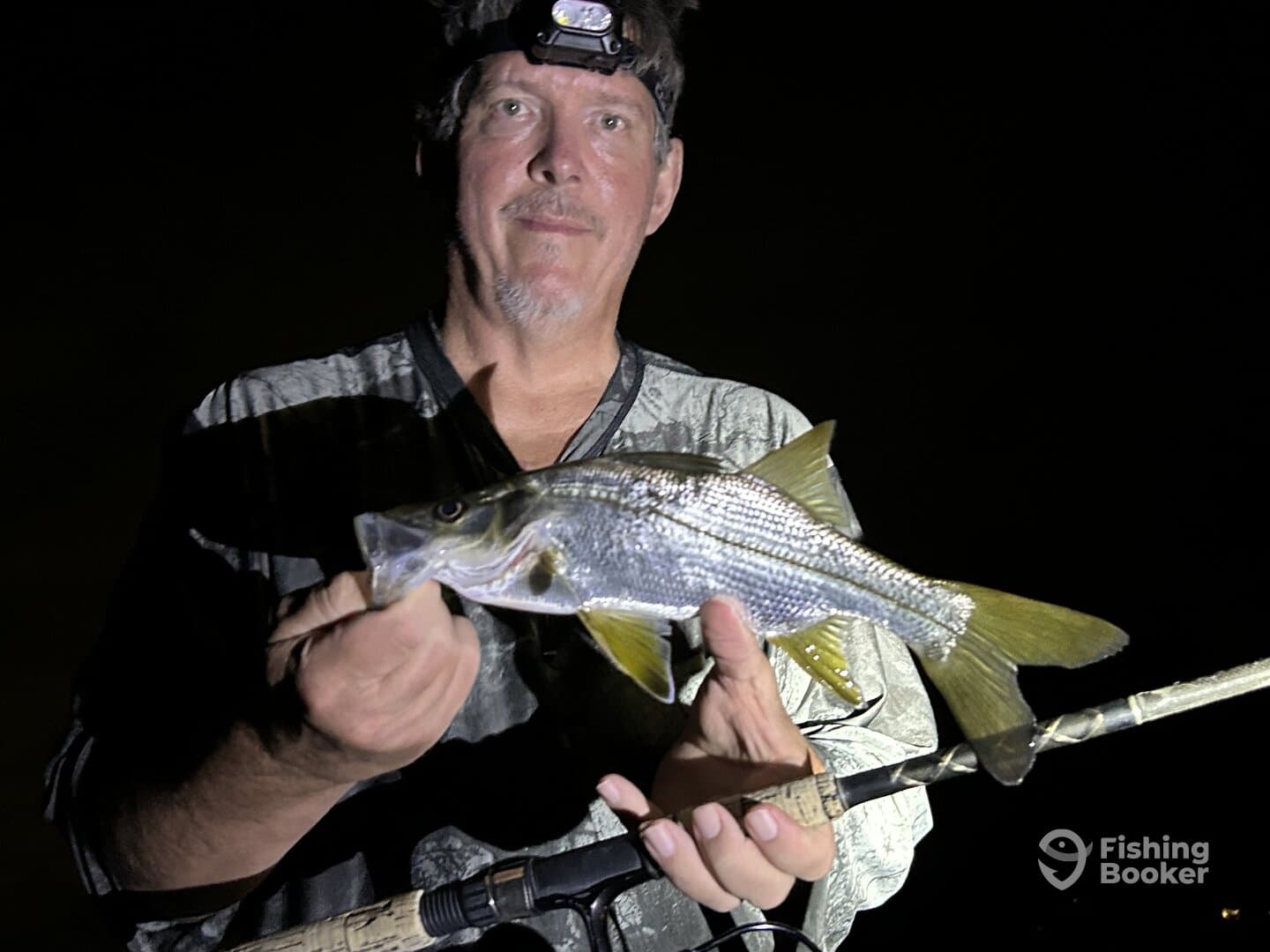 Angler proudly displaying a Snook caught during a night fishing session.