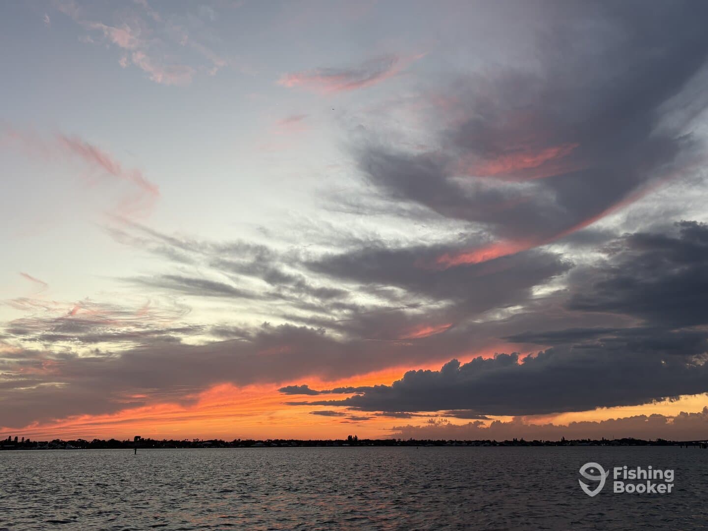 A scenic sunset over the water, showcasing vibrant colors in the sky, perfect for a tranquil fishing trip.