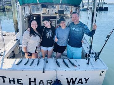 A family poses proudly on the boat 'The Hard Way' with their catch of several Spanish Mackerel after a successful fishing trip.