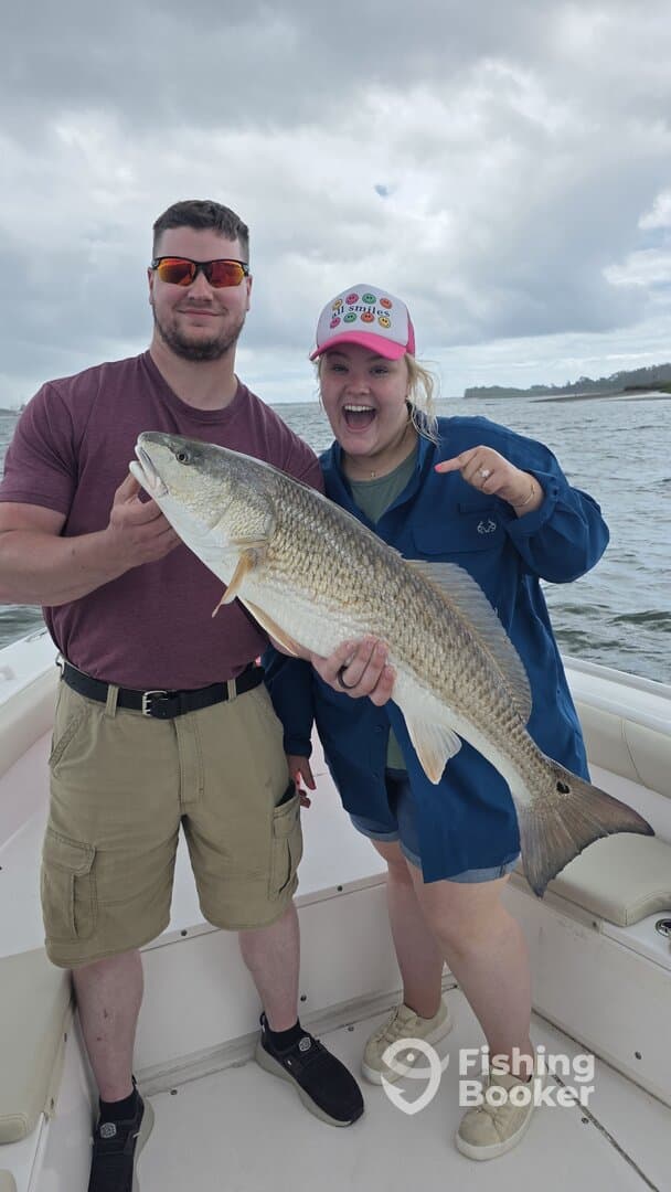Two anglers proudly displaying a large Redfish while enjoying a day on the water.