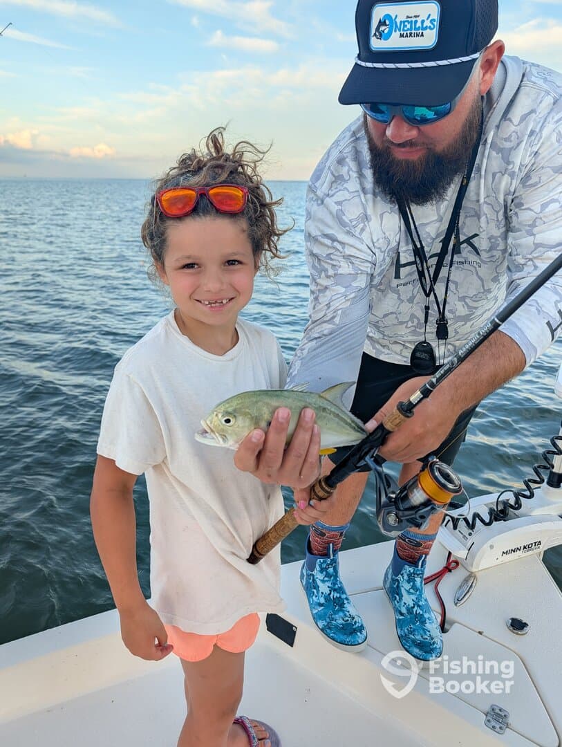 A young angler proudly displaying a small fish while fishing on a boat, enjoying a family outing on the water.