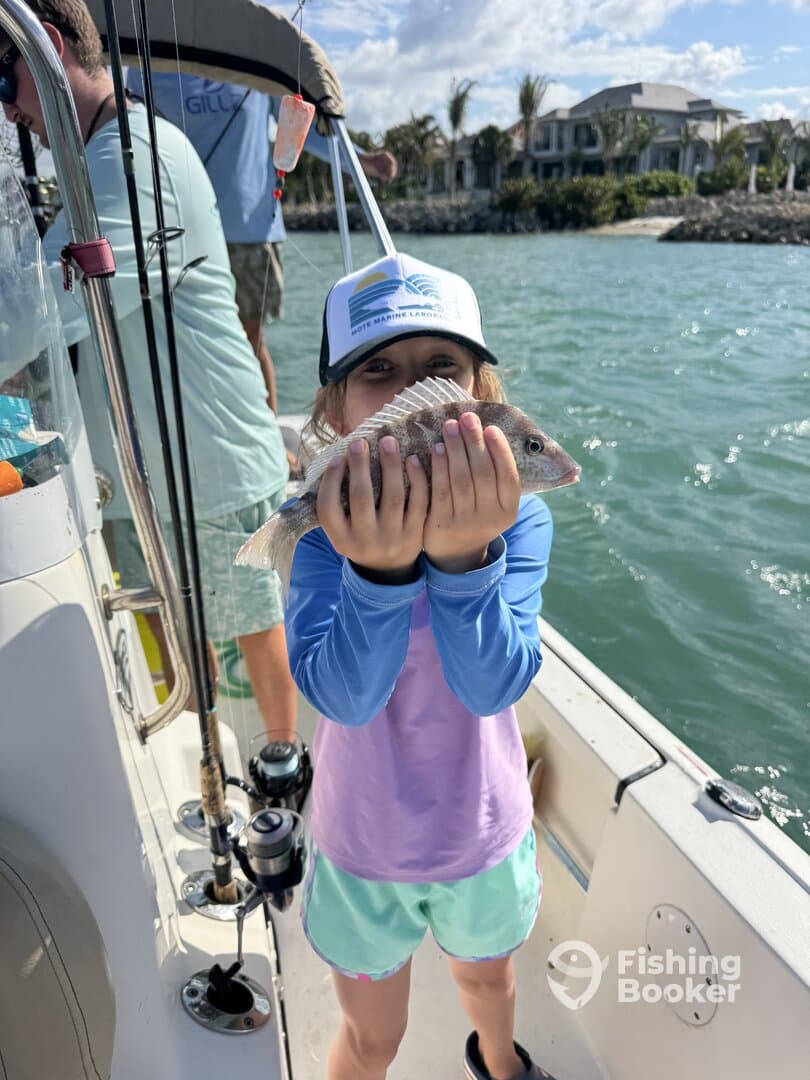 A young angler proudly holding a freshly caught fish while fishing on a boat, showcasing a fun family outing.