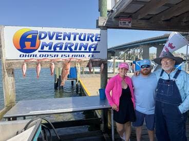 A group of anglers posing with their catch of red snapper and mahi-mahi displayed on a board at Adventure Marina, Okaloosa Island, FL.