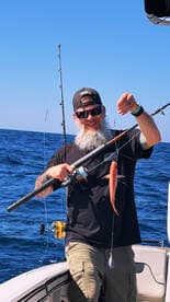 Angler proudly displaying a freshly caught fish while fishing offshore, showcasing a vibrant day on the water.