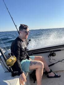 A young angler enjoying a day on the water, seated in a boat with fishing gear visible, showcasing a vibrant fishing environment.
