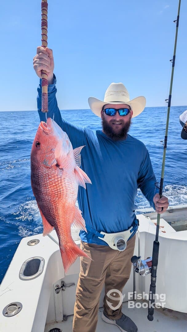 Angler proudly displaying a large Red Snapper while fishing on a boat in open waters.