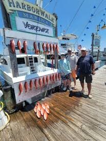 A family poses proudly in front of their catch of Red Snapper displayed on a board at Harborwalk Marina after a successful fishing trip.
