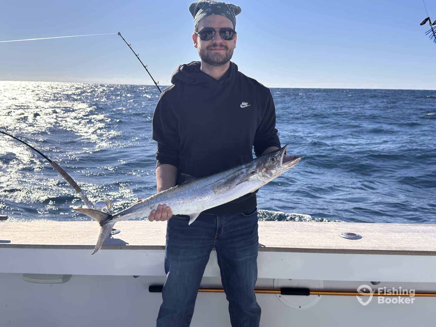 Angler proudly displaying a large King Mackerel while fishing offshore, showcasing a successful day on the water.