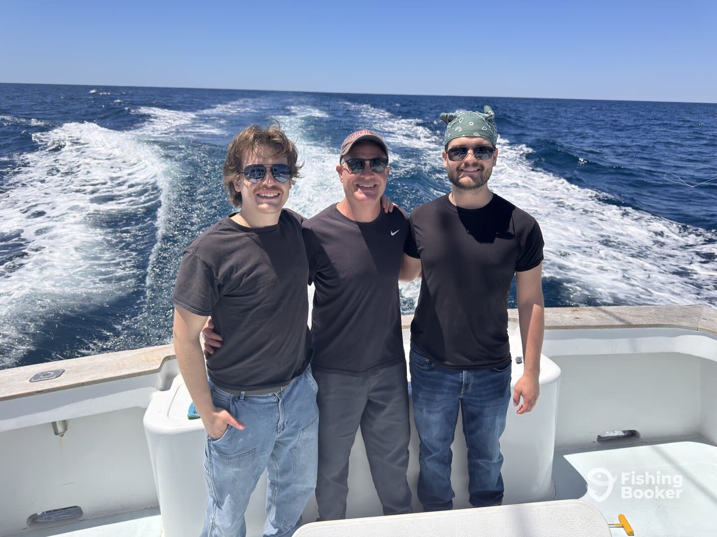 Three friends enjoying a sunny day on a fishing boat, with the ocean in the background.