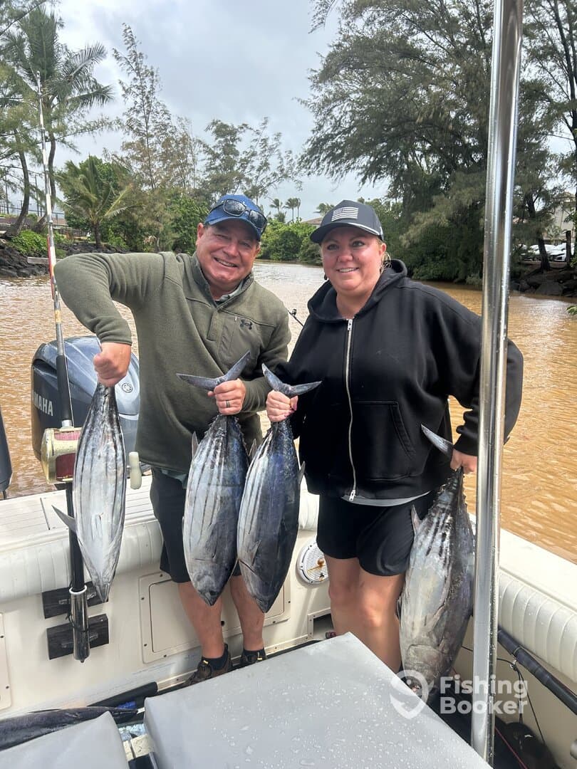 Two anglers proudly displaying their catch of four large Tuna on a fishing boat, showcasing a successful day on the water.