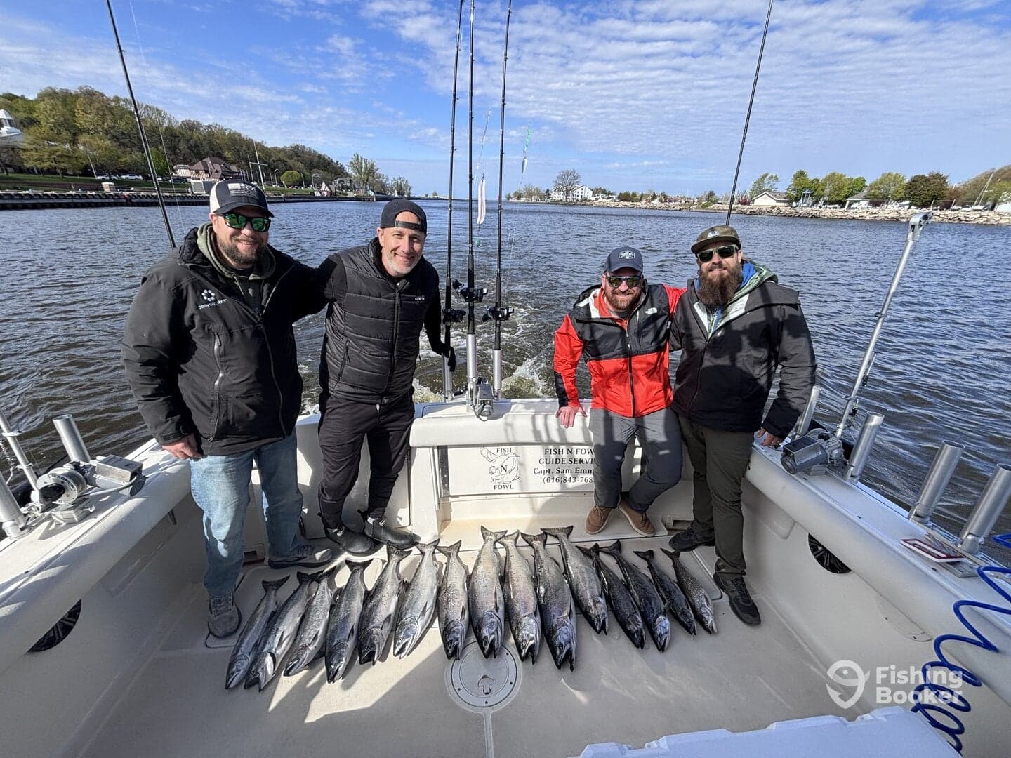 Four anglers proudly displaying their catch of salmon on the deck of a fishing boat, showcasing a successful day on the water.