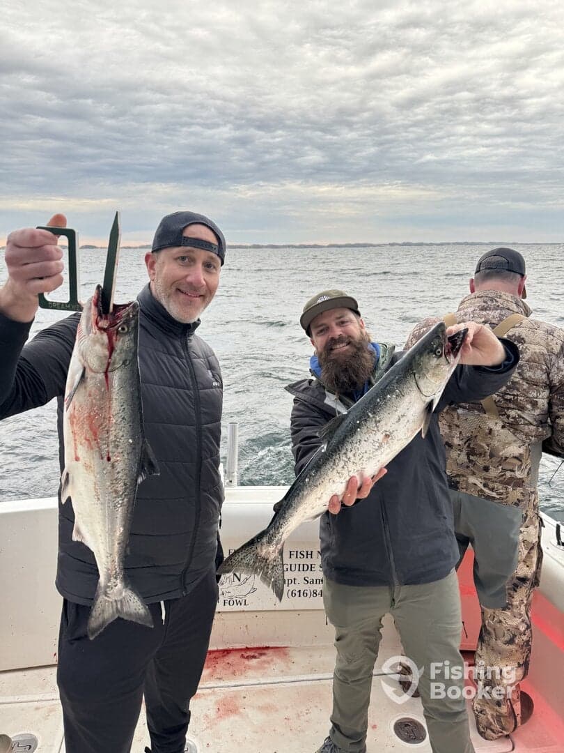 Two anglers proudly displaying their catch of Salmon while fishing on a charter boat.