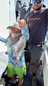 A young angler proudly displaying a Snapper while fishing on a charter boat, showcasing a fun family fishing experience.