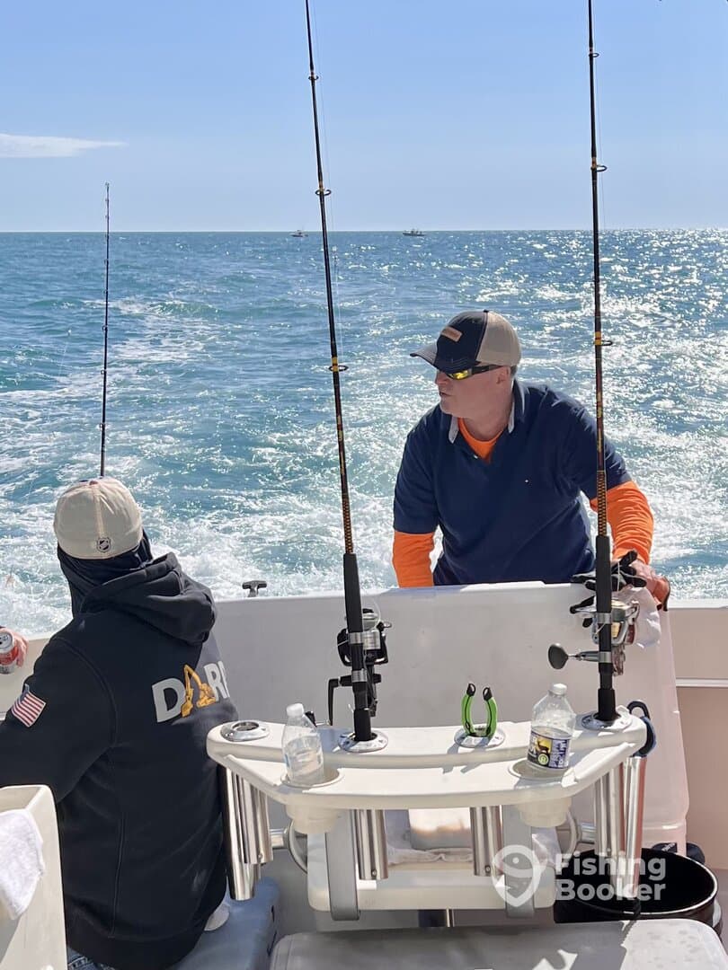 Two anglers engaged in fishing on a sunny day, with multiple fishing rods set up on the boat, showcasing a lively fishing environment.