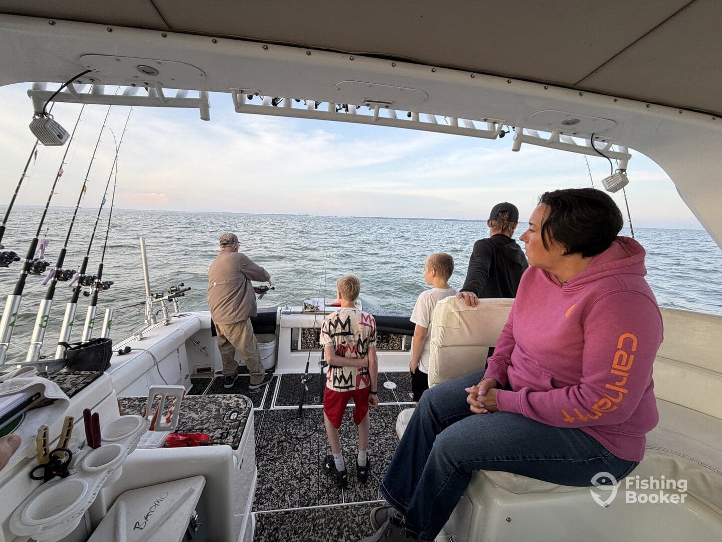 A family enjoying a fishing trip on a boat, with children observing the fishing action as an adult prepares to reel in a catch.